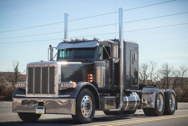 A dark gray semi truck is driving down a highway.