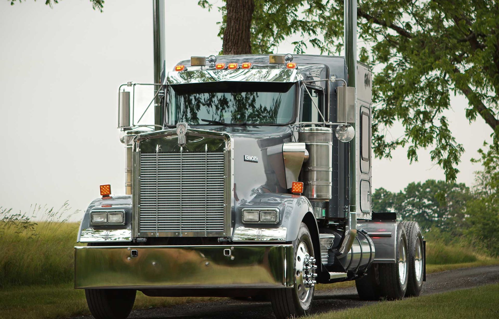 A silver semi truck is parked on the side of a road