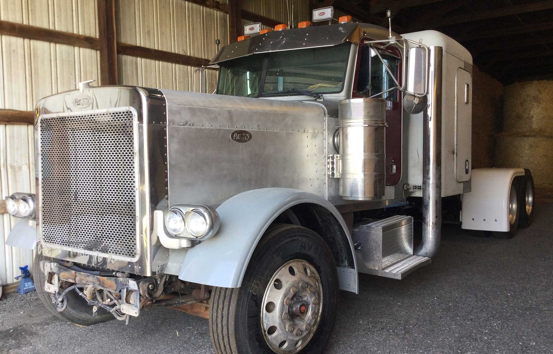 A silver semi truck is parked in a garage