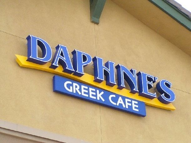 A blue and yellow sign for daphines greek cafe