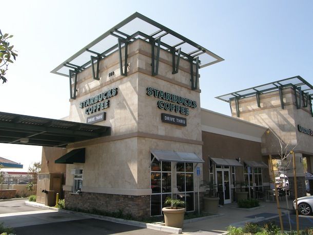 A starbucks coffee store with a car parked in front of it