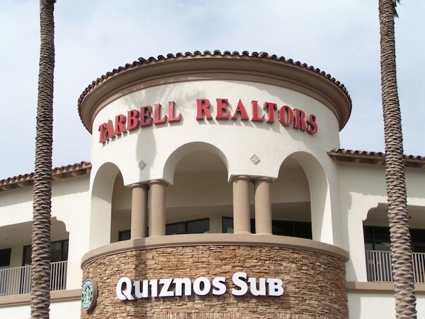 A building with a sign that says mrbell realtors quiznos sub