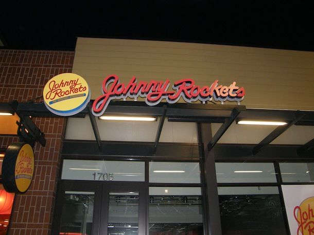 The front of a johnny rockets restaurant at night