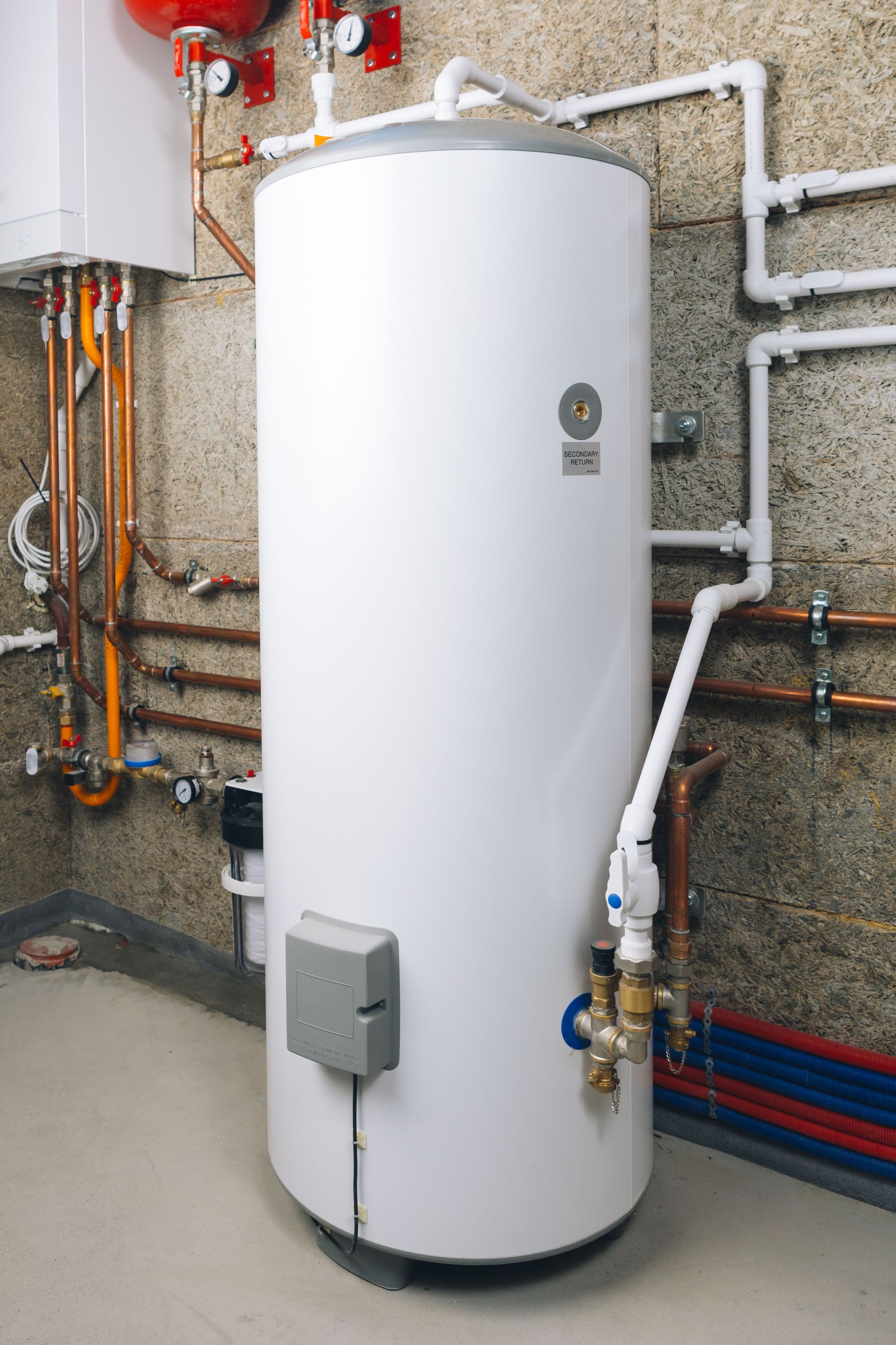 White water heater tank in a basement setting with copper pipes.