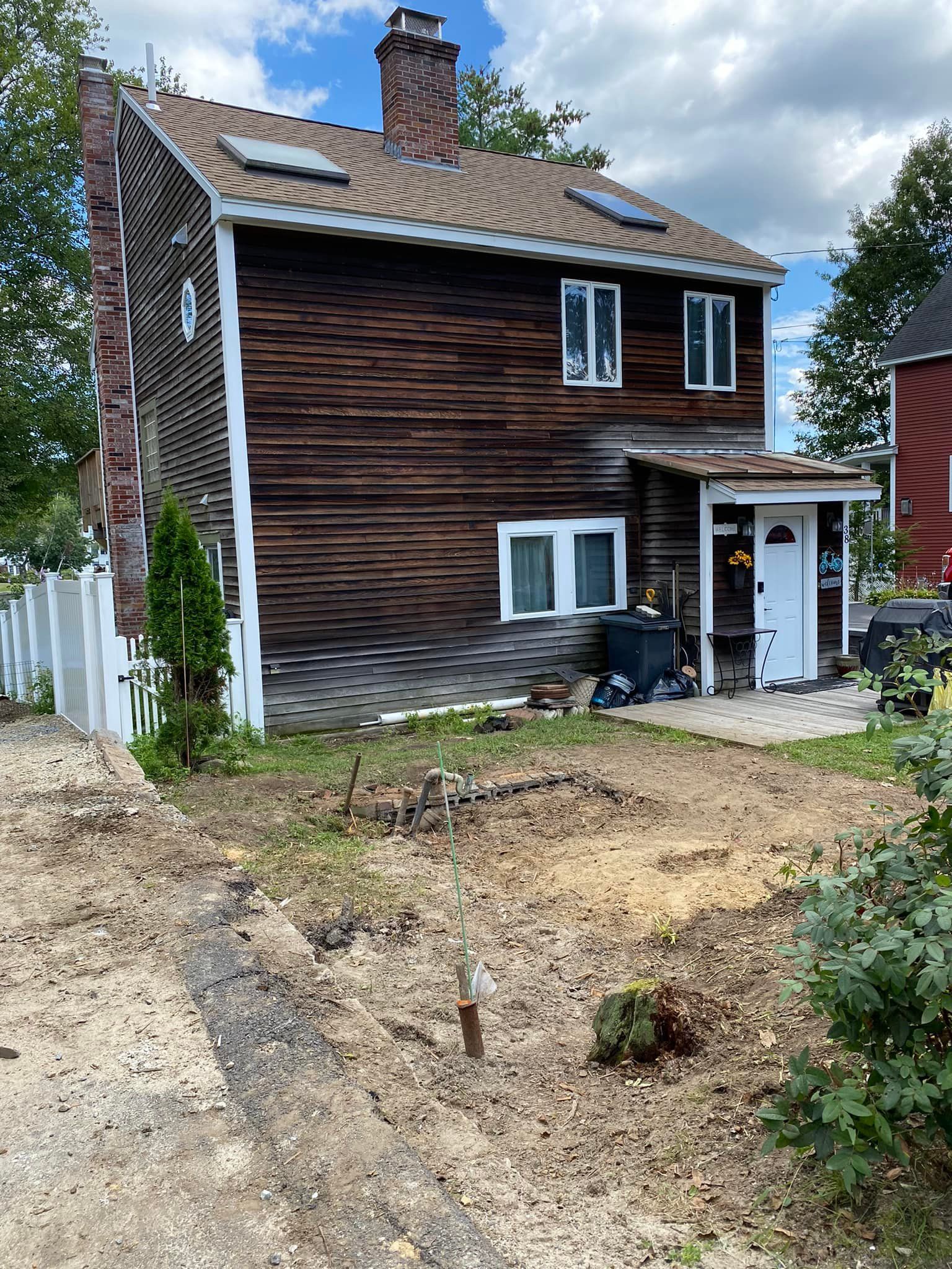 Brown wooden house with white trim, fence, and a dirt yard.