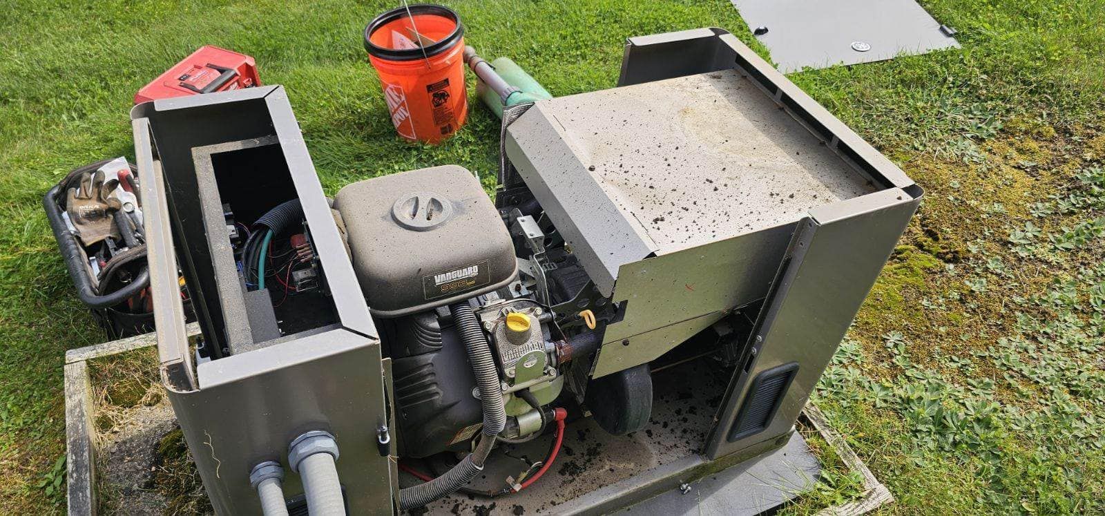 Generator with an open compartment, engine visible, sitting outside on the grass.