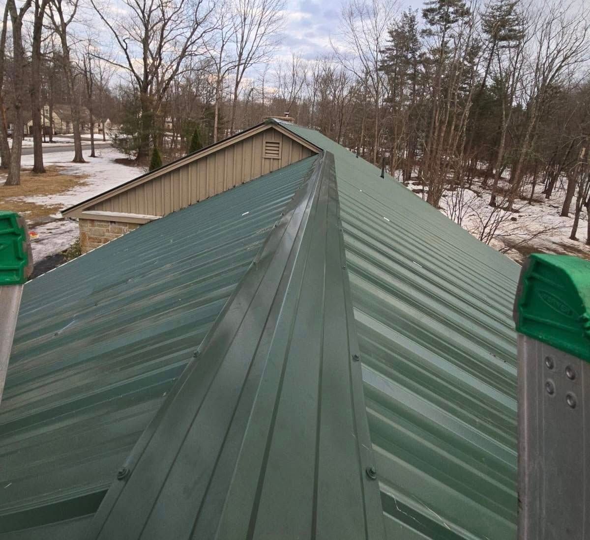 Green metal roof with ridge flashing, outdoors.