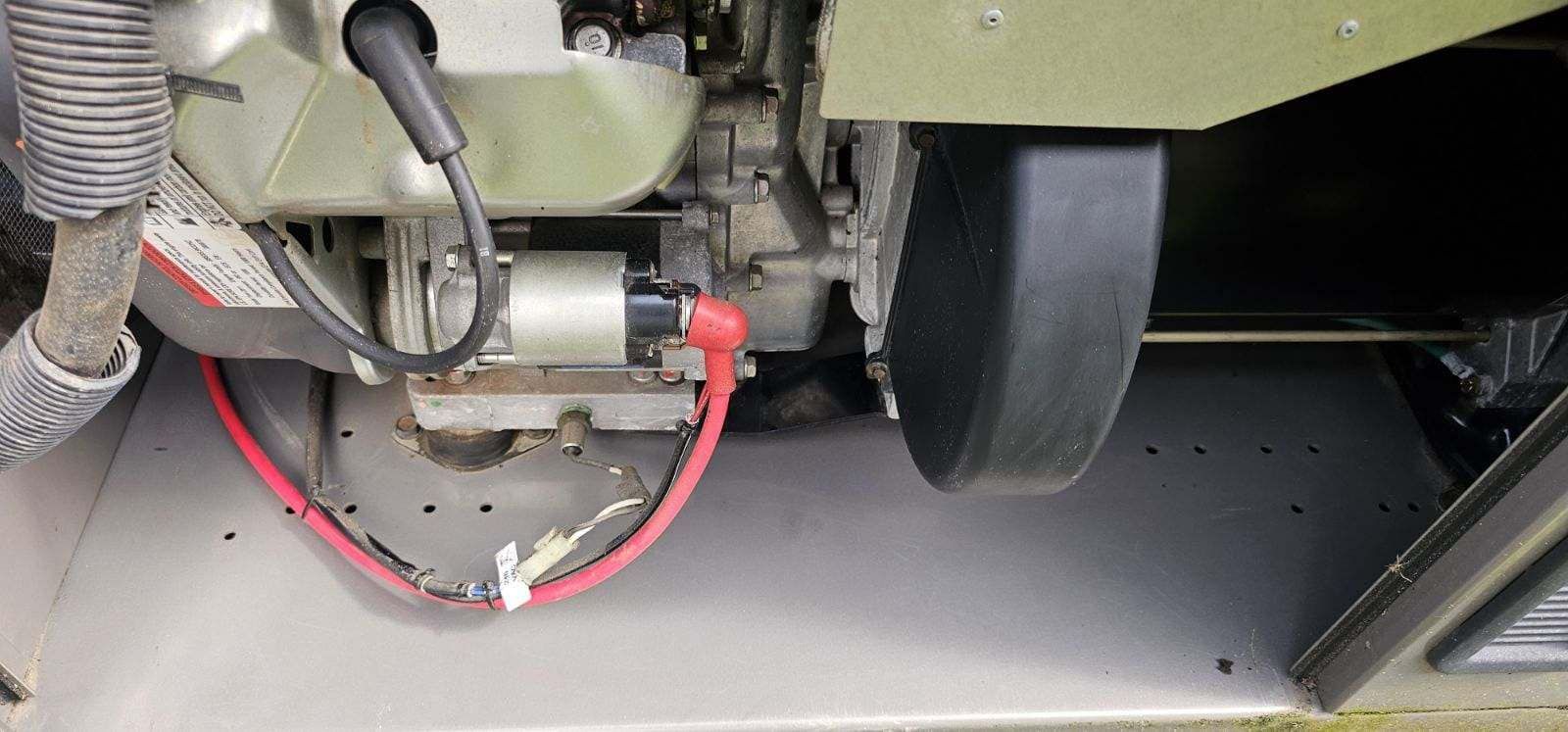 Close-up of a small engine showing a red cable connected to the starter.