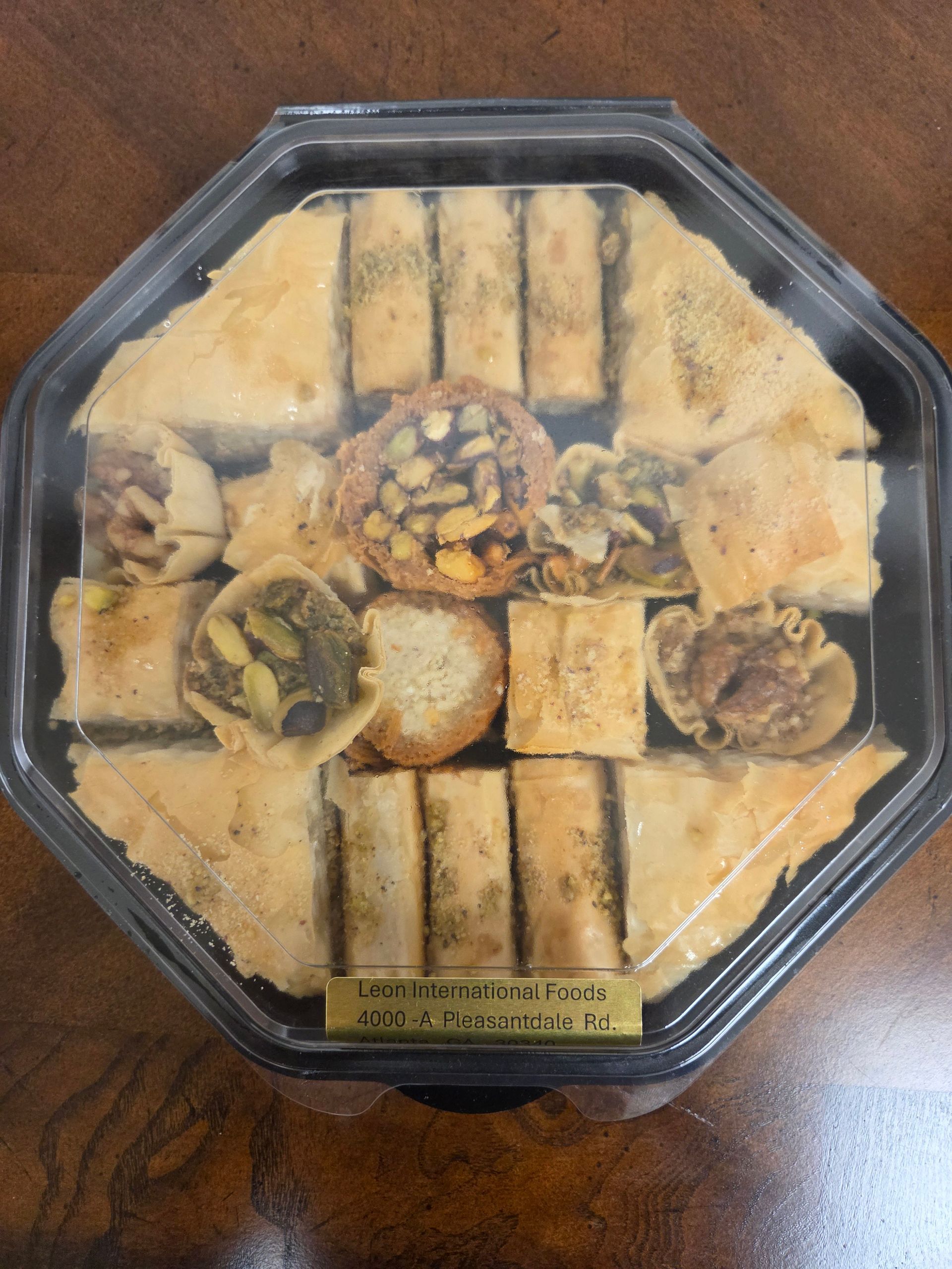 Octagonal box of assorted pastries on a wooden table, wrapped in clear plastic.