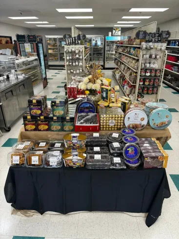 Gift display table in a store aisle with assorted boxed and packaged items on black cloth.