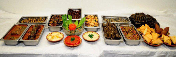 A table spread of various Middle Eastern dishes in trays and bowls.