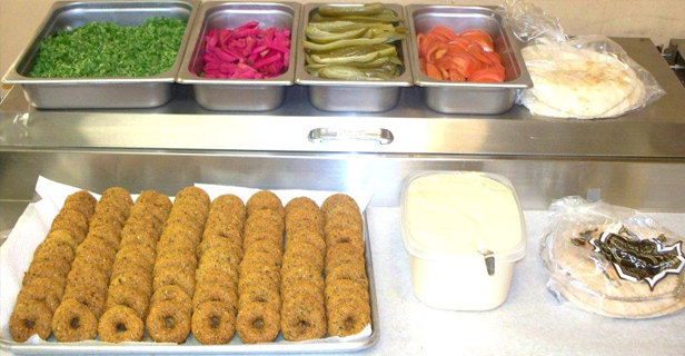 Falafel bar: Falafel patties, toppings (greens, pickled veggies, tomatoes), pita, and tahini.