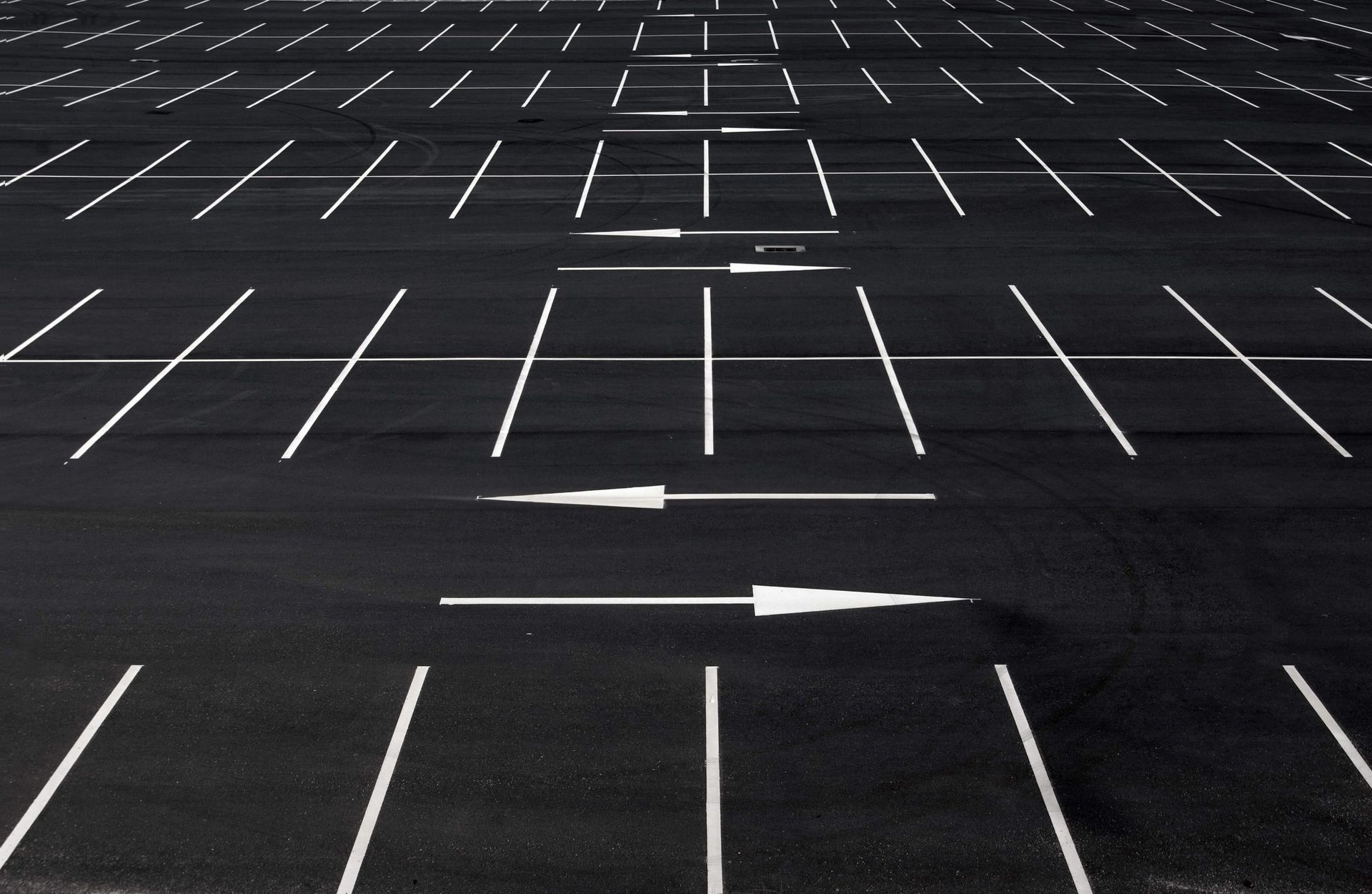 An empty parking lot with white arrows pointing in opposite directions