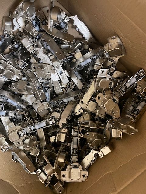 A box filled with a lot of hinges on a table.