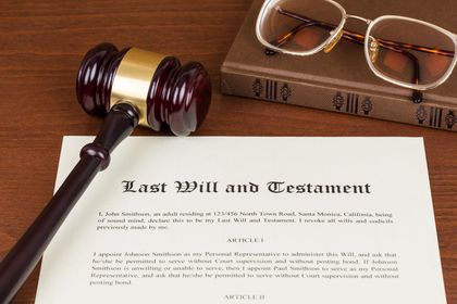 A wooden gavel sitting on top of a last will and testament