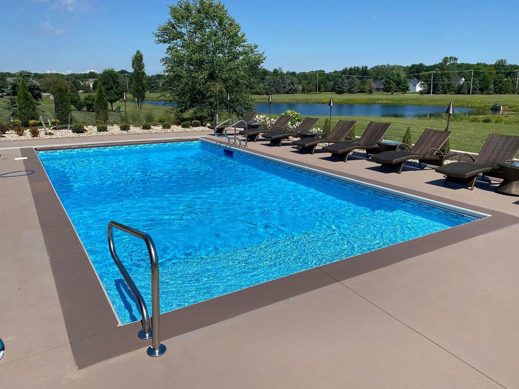 Outdoor swimming pool with blue water, lounge chairs, and a lake in the background
