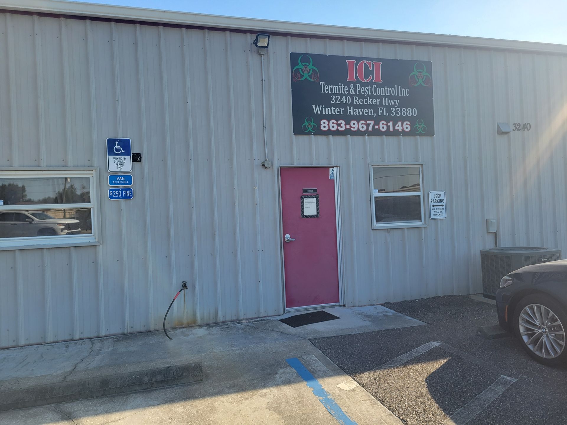 A car is parked in front of a building with a pink door.