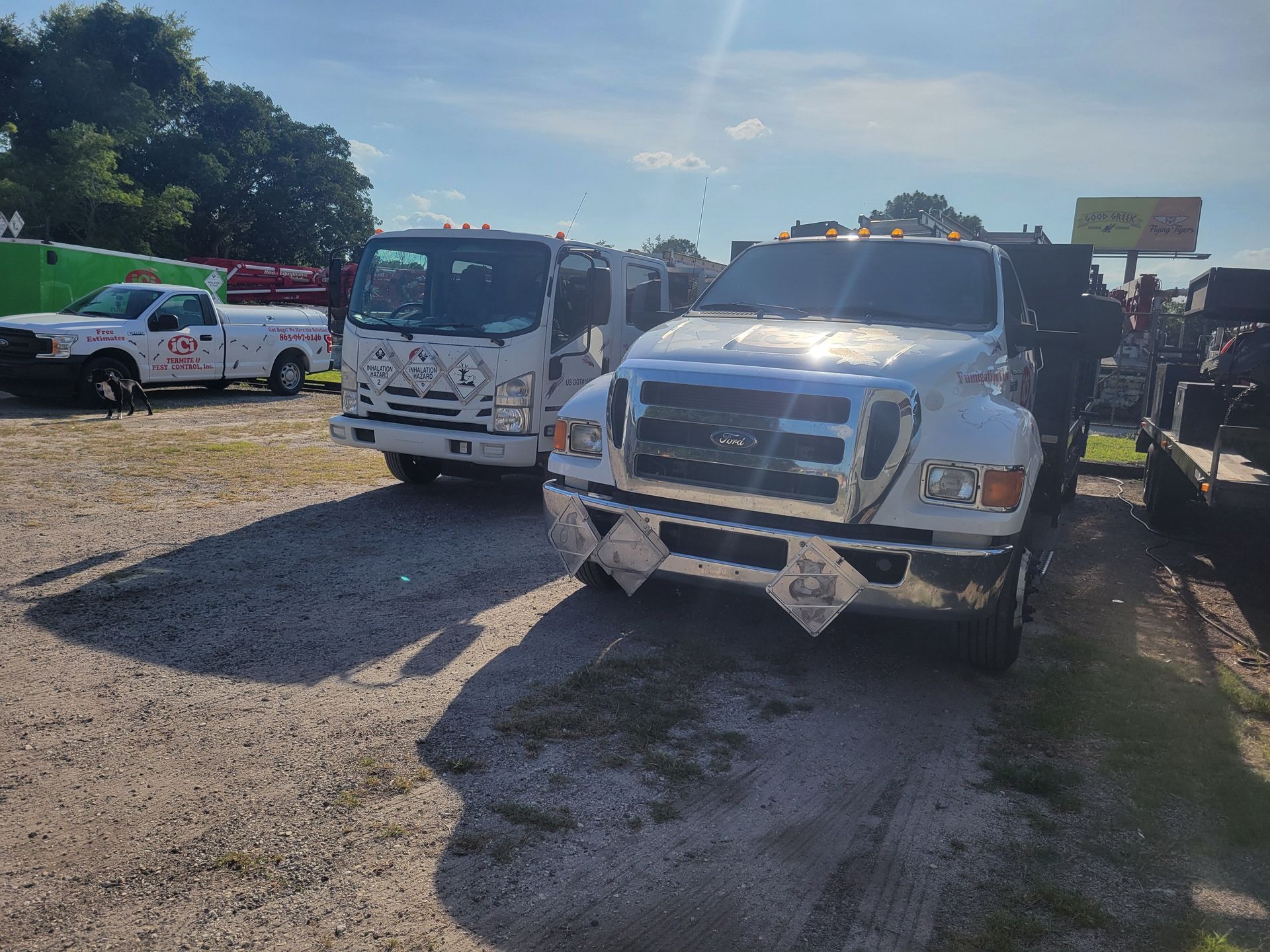 A group of trucks are parked in a gravel lot.