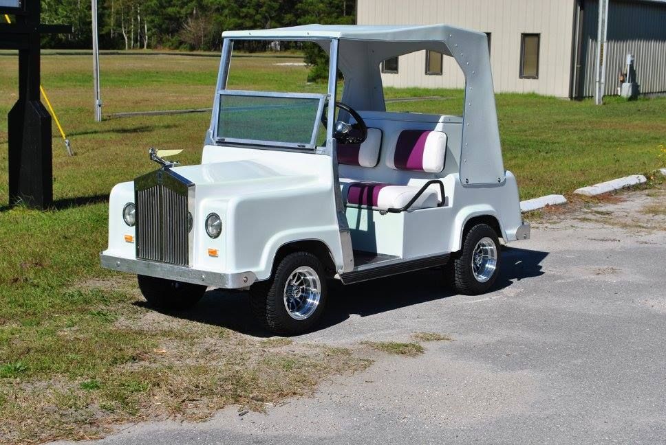 A white golf cart is parked on the side of the road.