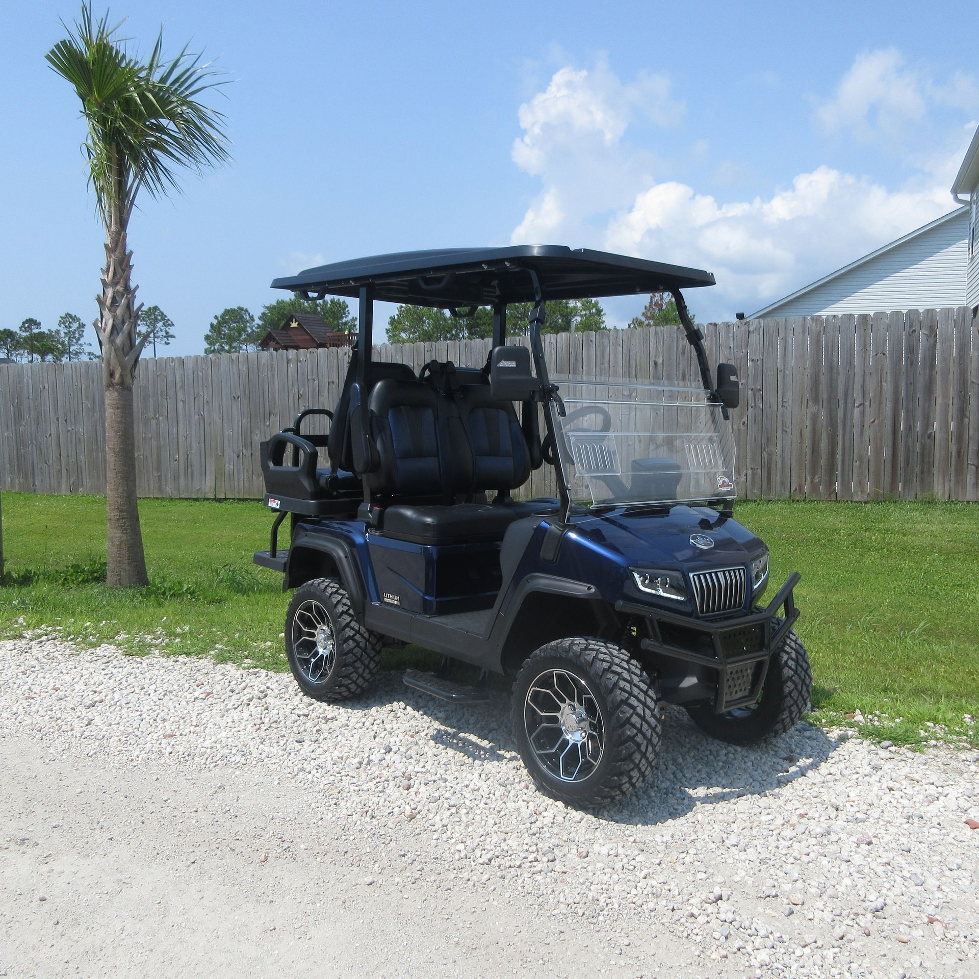 A blue golf cart is parked on a gravel road