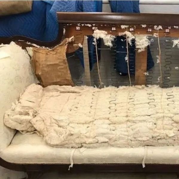Damaged beige sofa with torn upholstery and exposed springs, showing ripped padding and frame.
