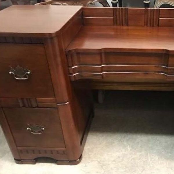 Dark wood office desk with drawers and curved front on a light floor
