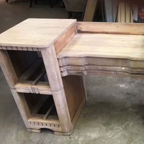 Unfinished wooden desk with stepped shelves and a curved front on a concrete floor.