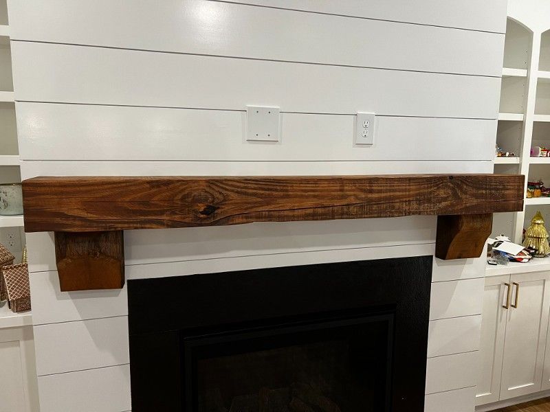 A fireplace with a wooden mantle in a living room.