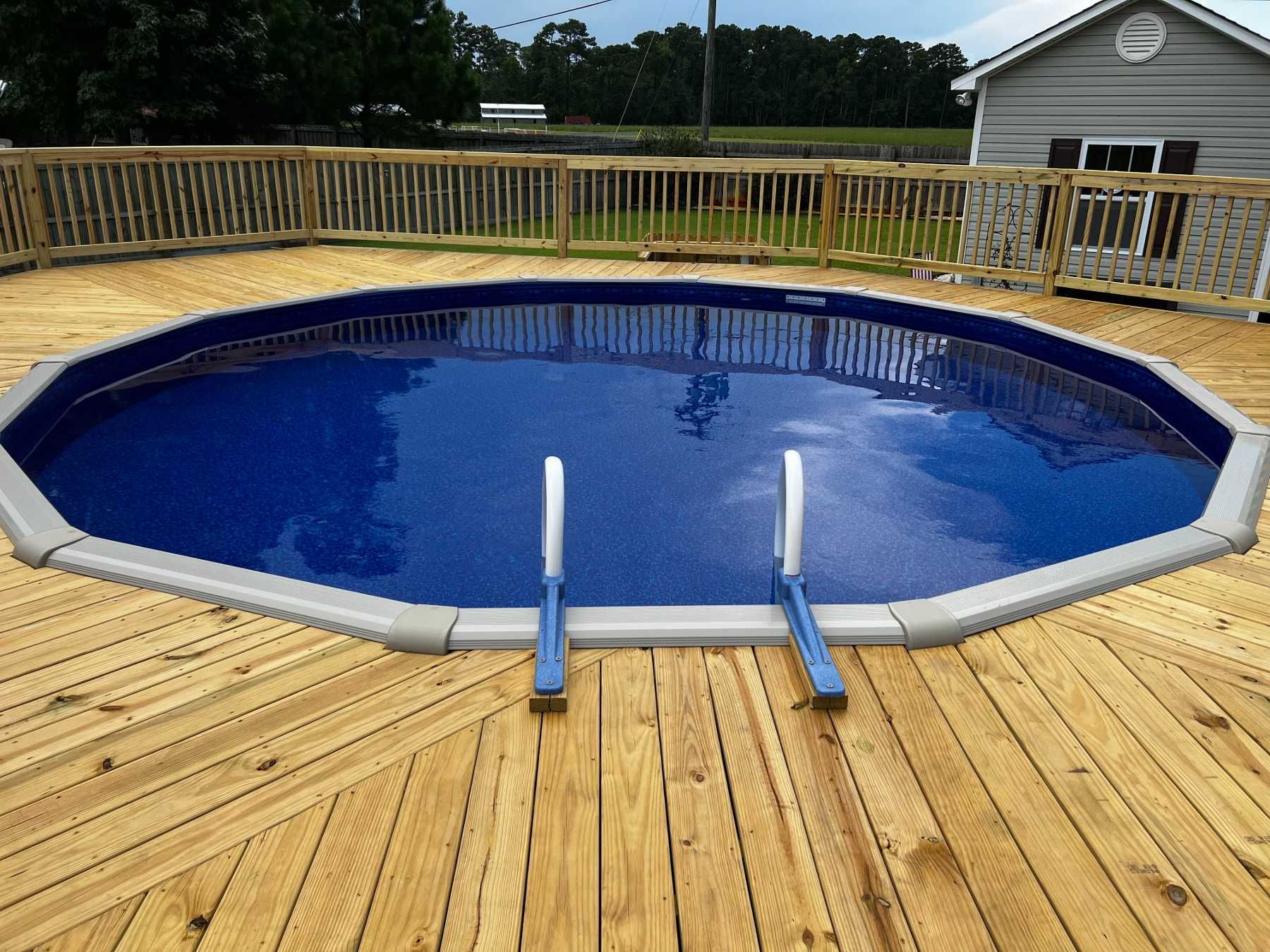 A swimming pool is sitting on top of a wooden deck.