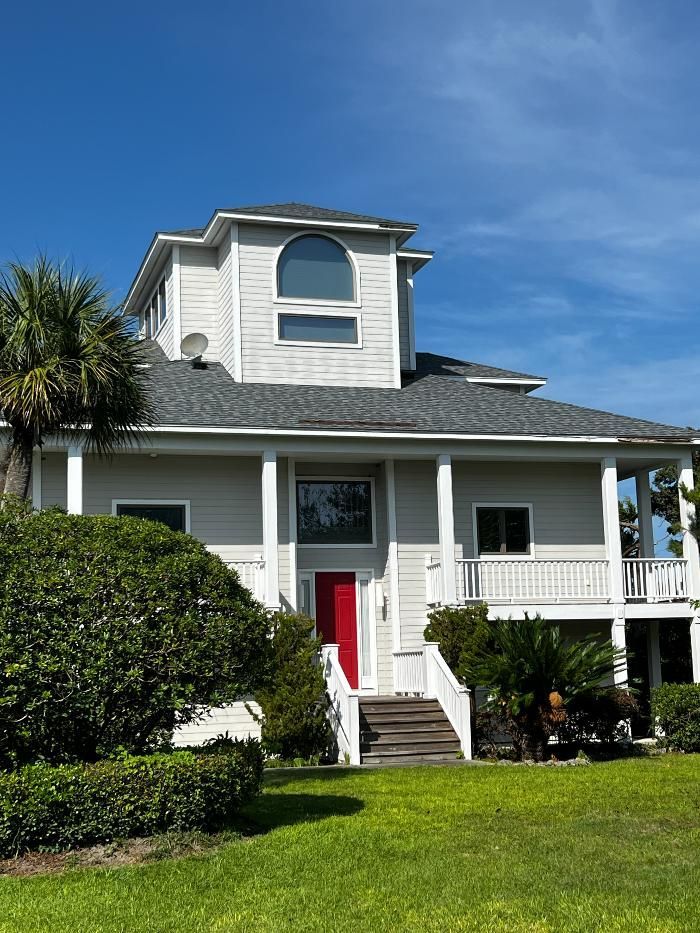 A large white house with a red door and stairs