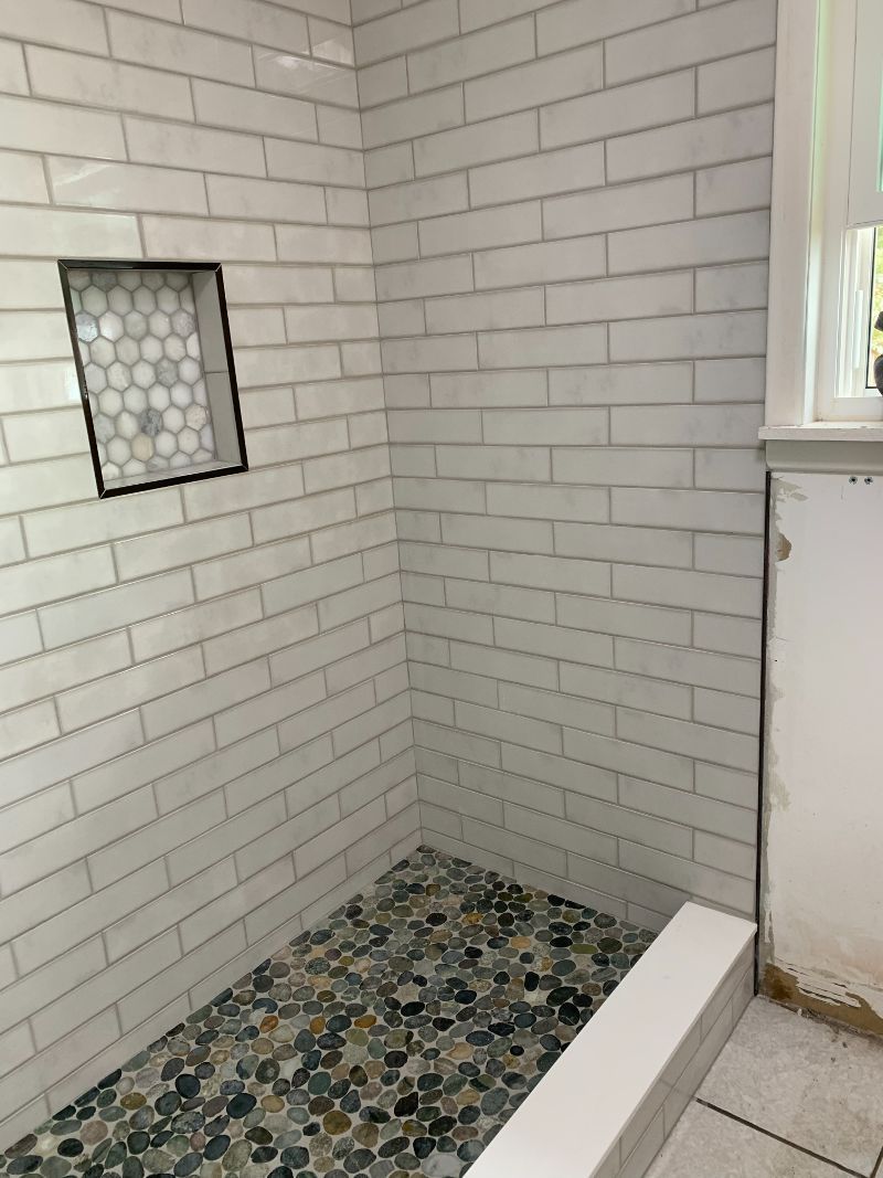 A bathroom with white brick walls and a walk in shower
