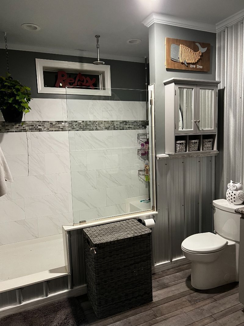 A bathroom with a toilet , sink , shower and mirror.