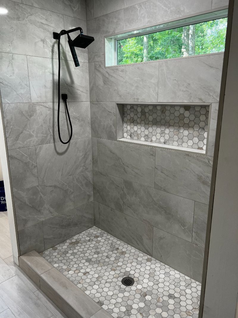 A walk in shower with a window and a shower head.