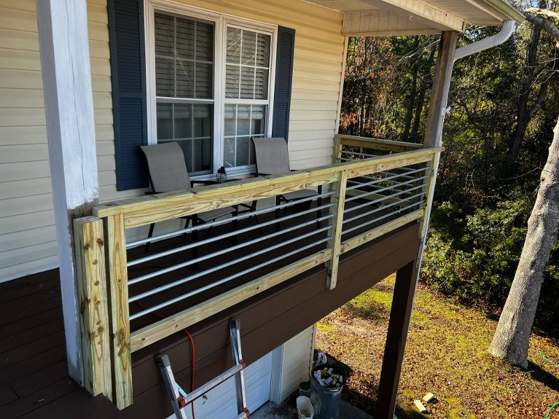 A wooden deck with a metal railing is attached to the side of a house.