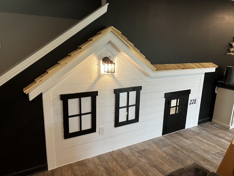 A playhouse is built into the wall under a staircase.