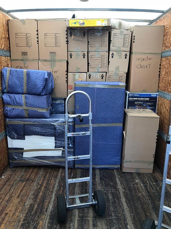 A moving truck filled with boxes and a dolly.