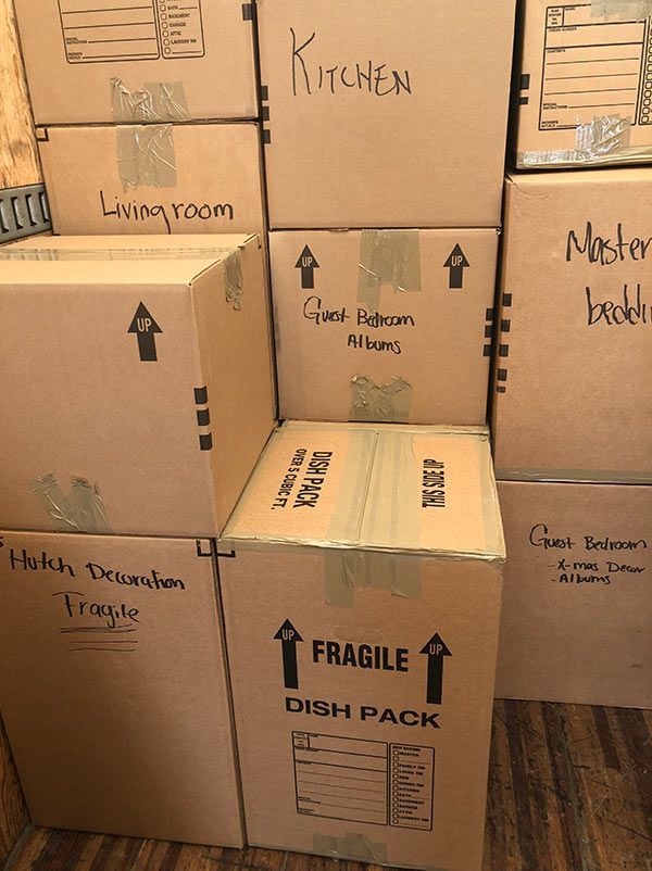 A stack of cardboard boxes labeled kitchen and fragile dish pack