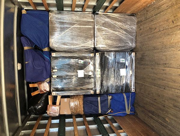 The inside of a moving truck filled with boxes wrapped in plastic.