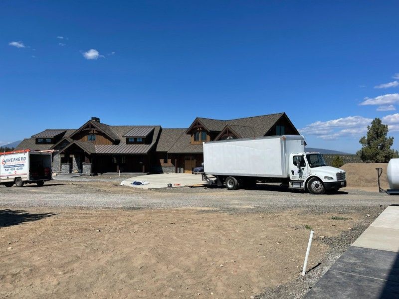 A white truck is parked in front of a large house.