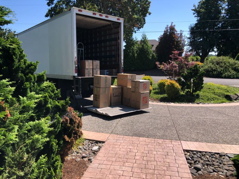 A moving truck filled with boxes is parked on the side of the road.