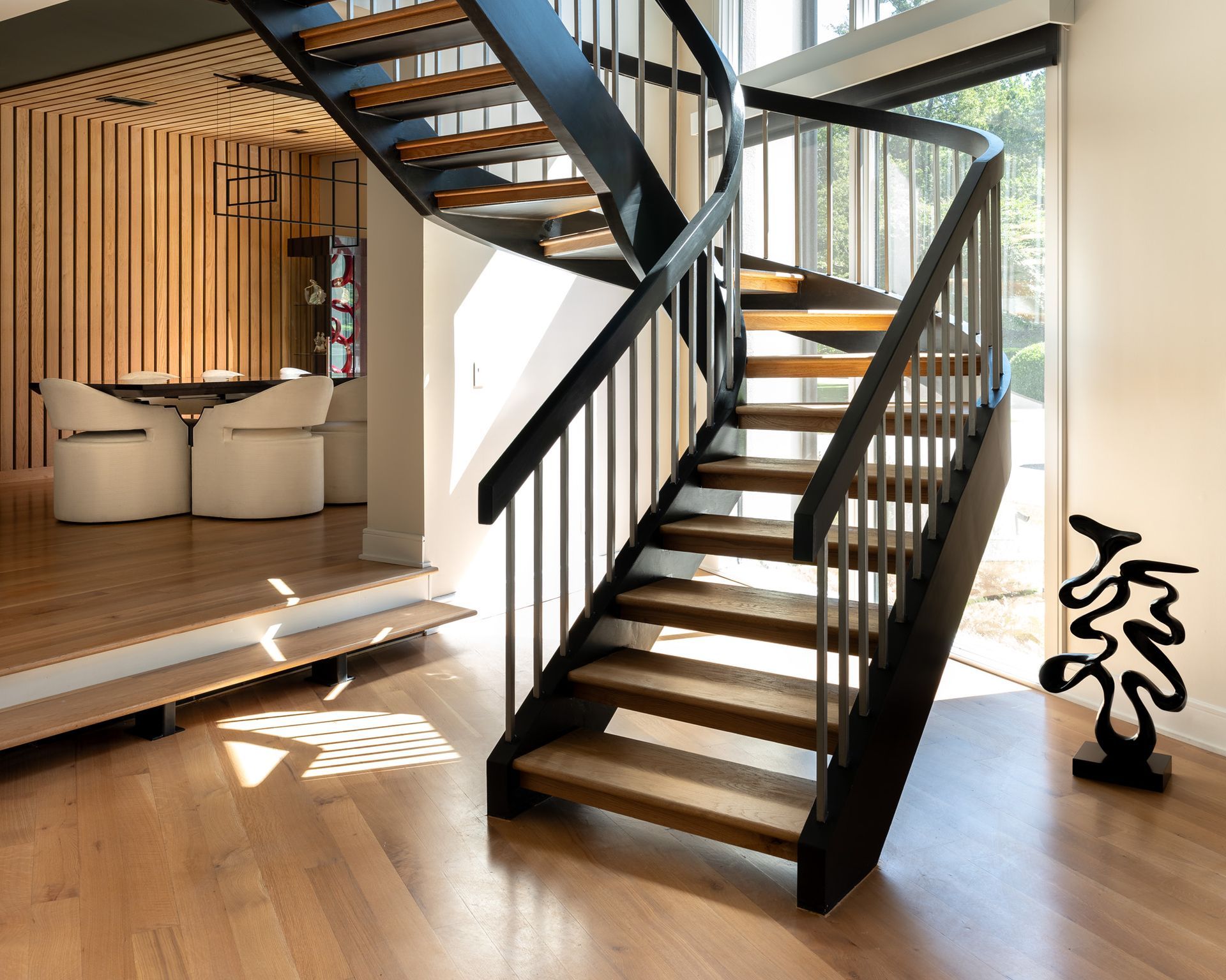 A wooden staircase with black metal railings in a modern home with wood floors and accents.