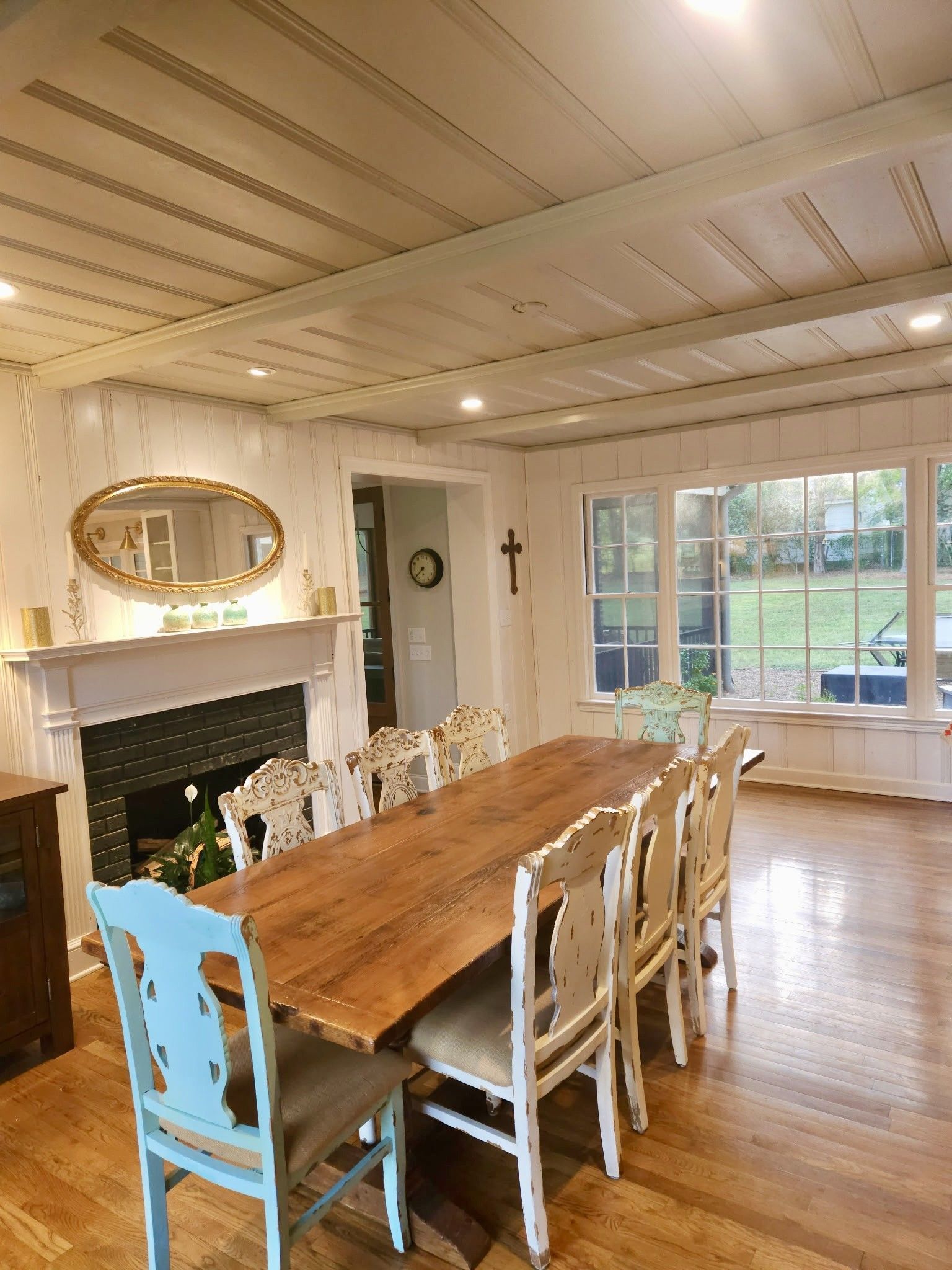 Dining room with a long wooden table, fireplace, and large windows.