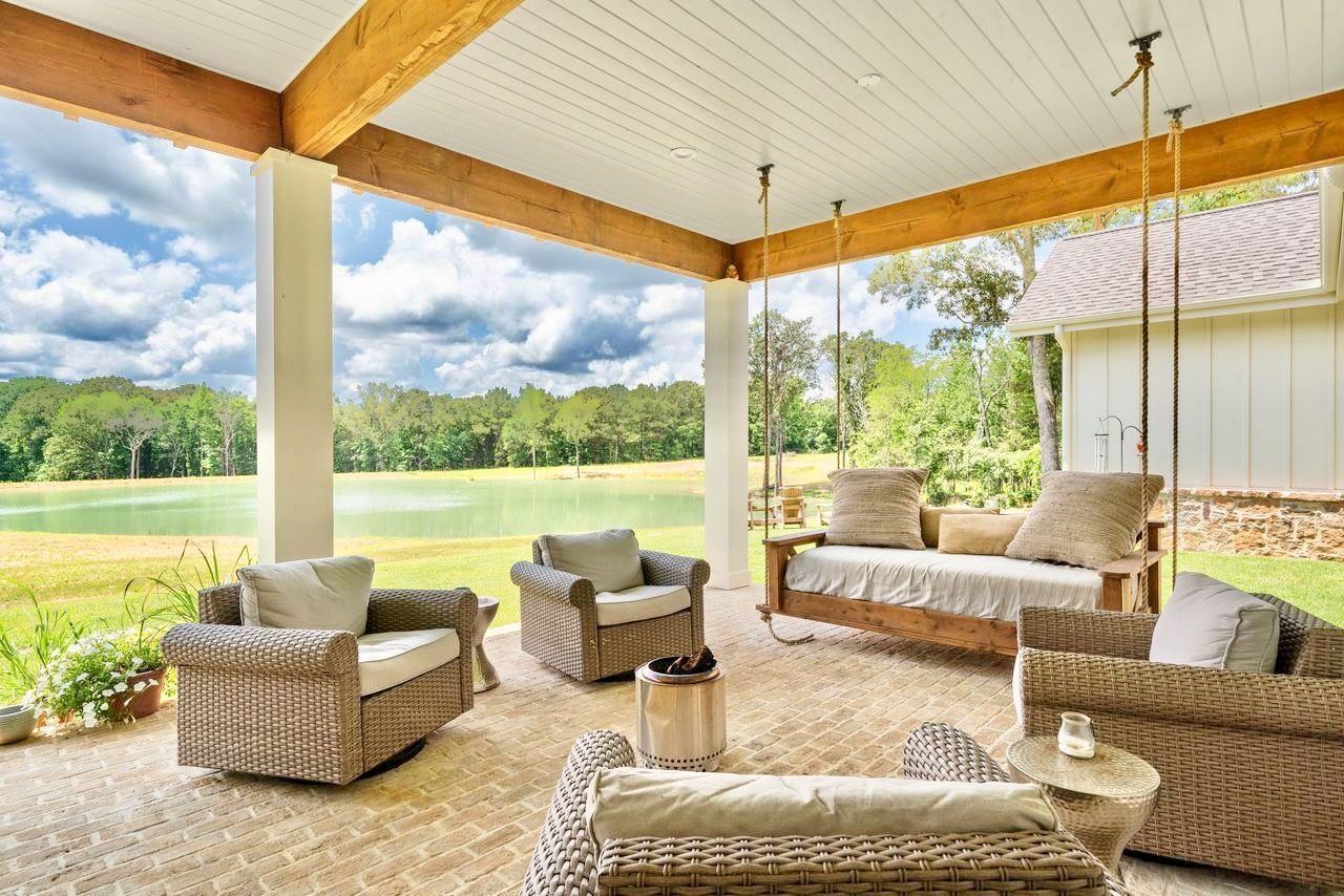 Covered patio with wicker furniture, swing, and scenic lake view.