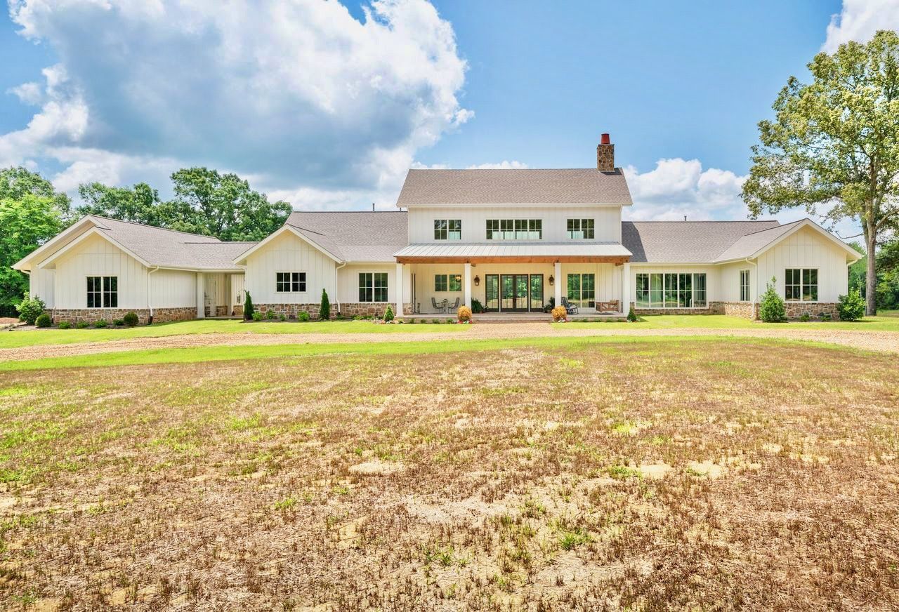 White farmhouse with brick accents and a large yard.