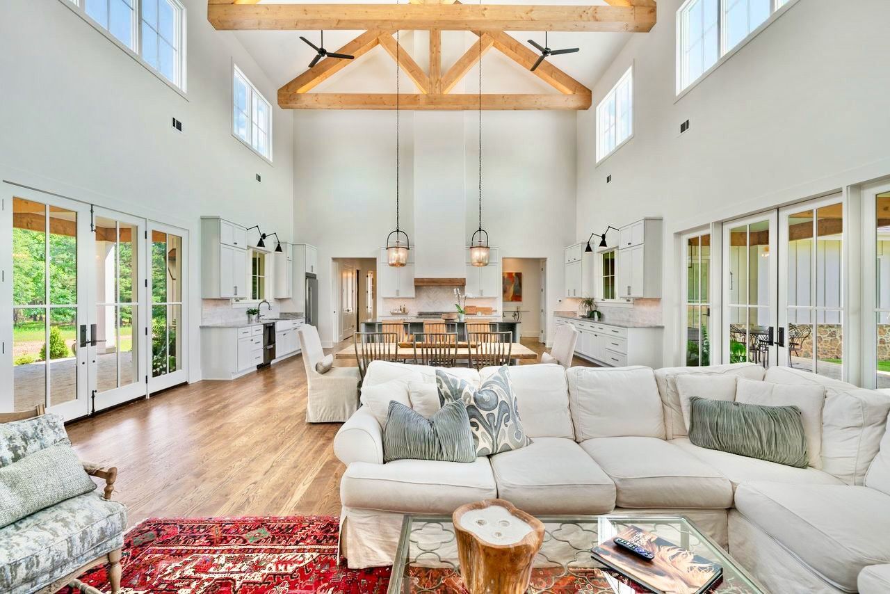 Spacious living room with high ceilings, white walls, and a large white sectional.