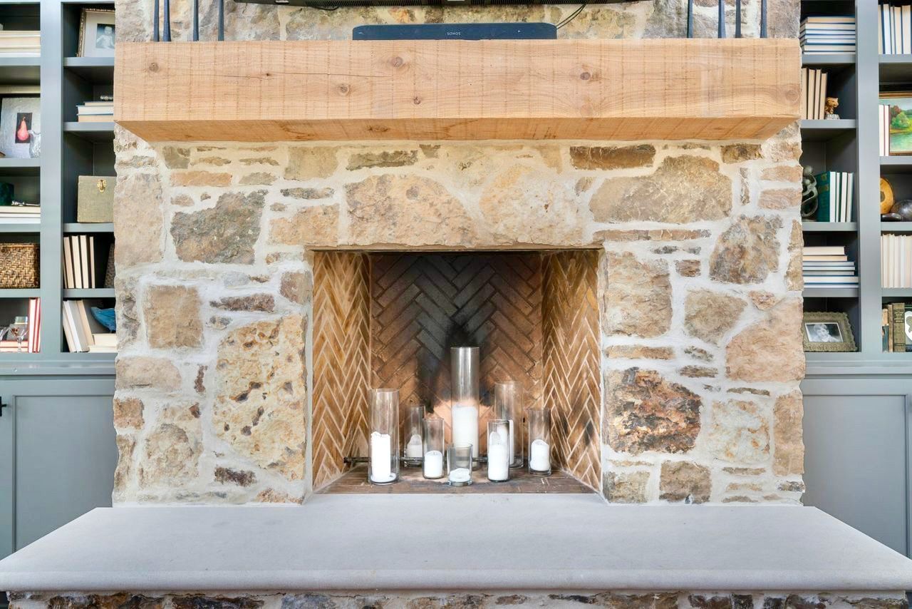 Stone fireplace with candles, wooden mantel, and built-in bookshelves.