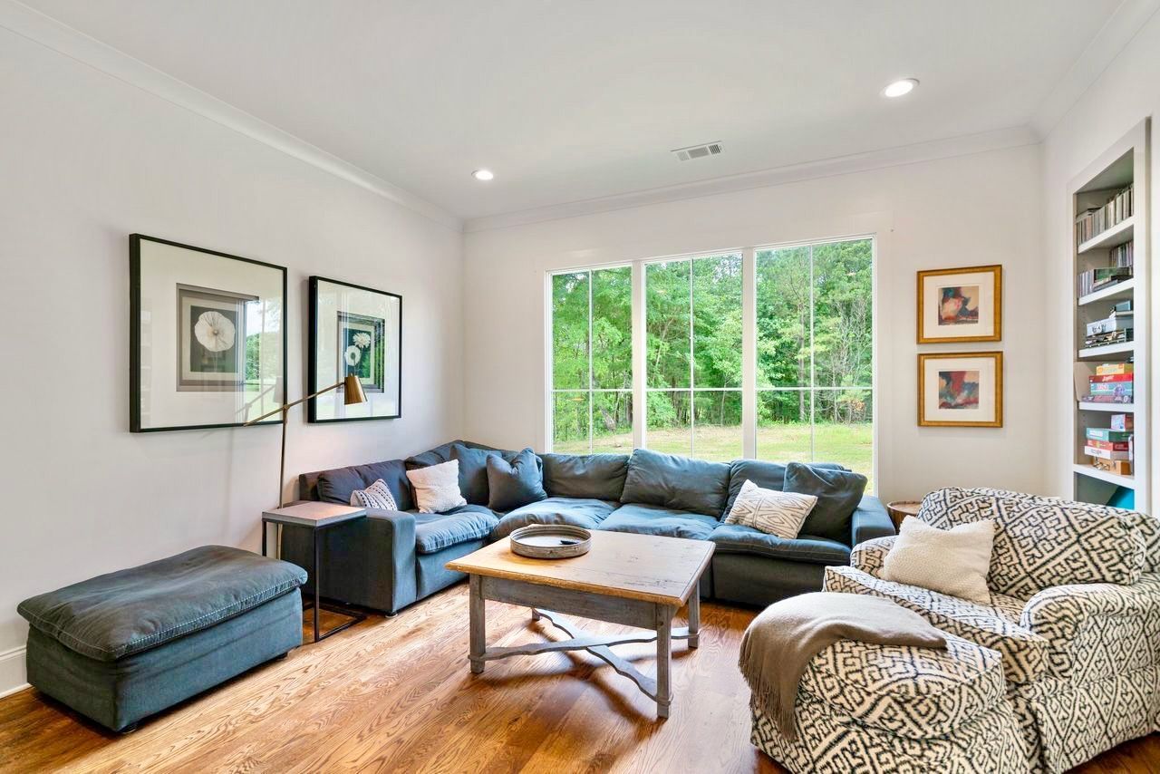 Living room with blue sectional sofa, armchair, coffee table, and large window overlooking trees.