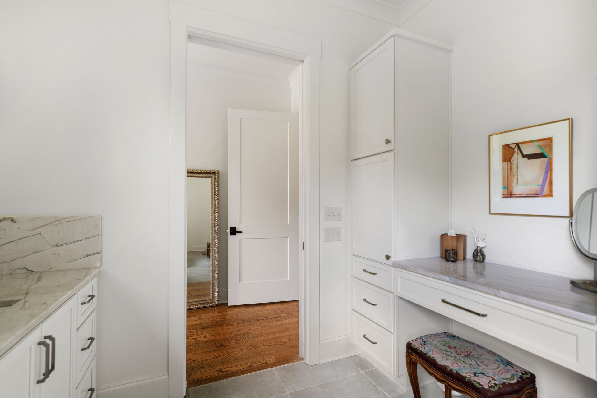 White bathroom with vanity and cabinets open door reveals a mirror.