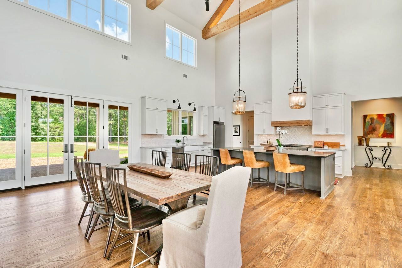 Spacious kitchen and dining area with high ceilings, wooden floors, and natural light.