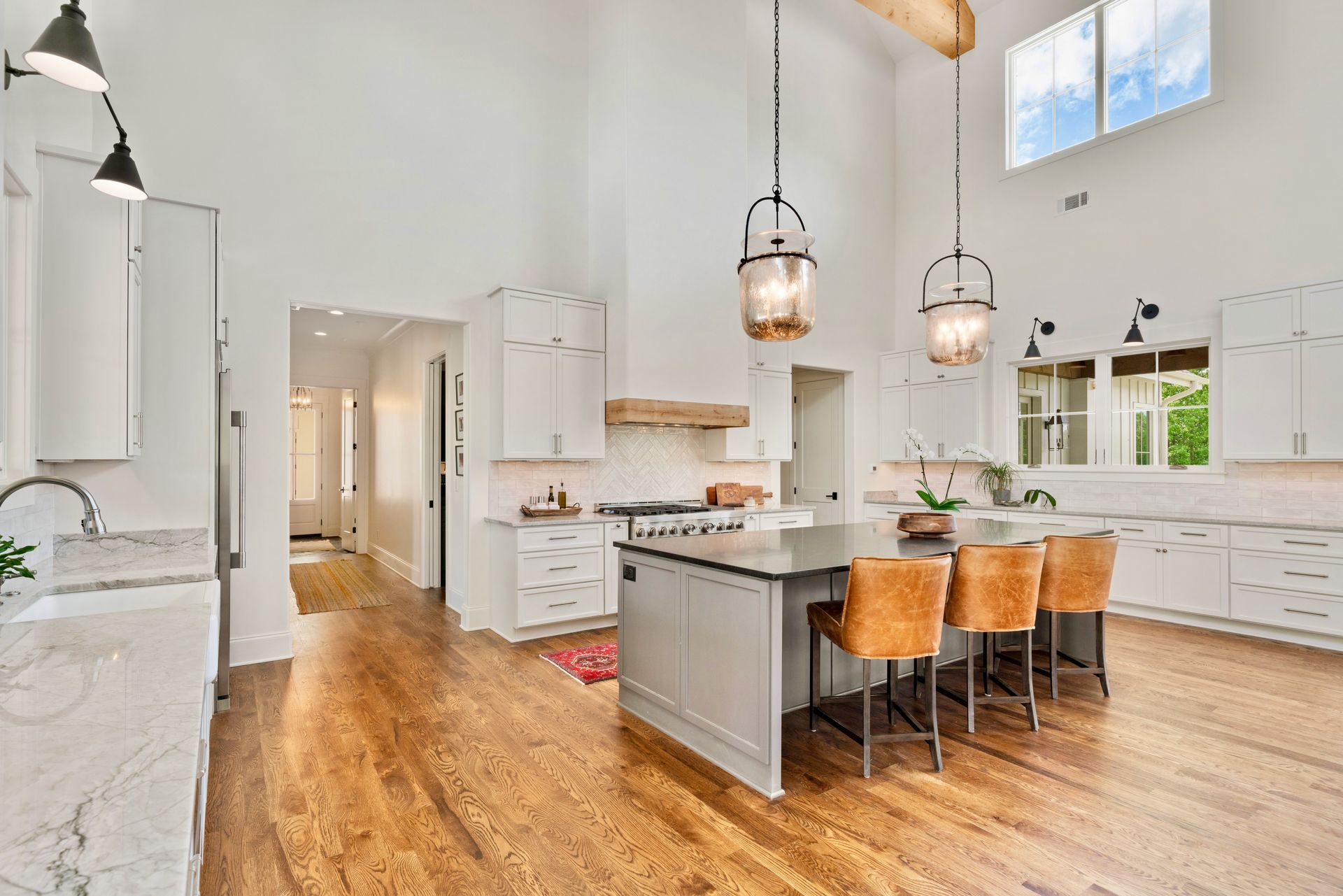 Spacious white kitchen with island seating, hardwood floors, and high ceilings.